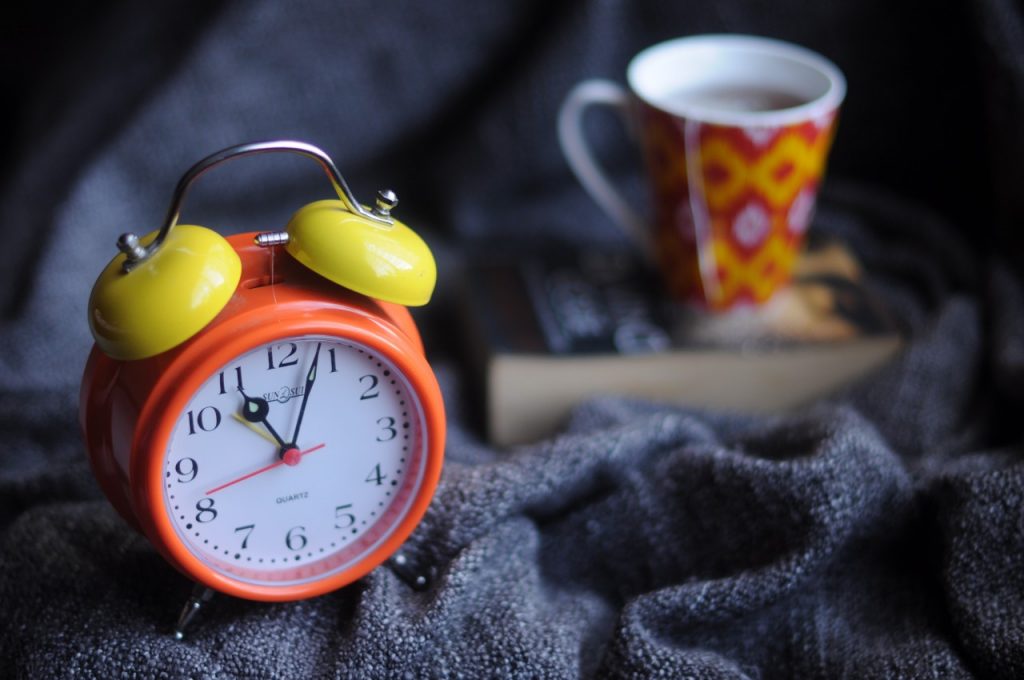 Red and orange alarm clock with mug of tea